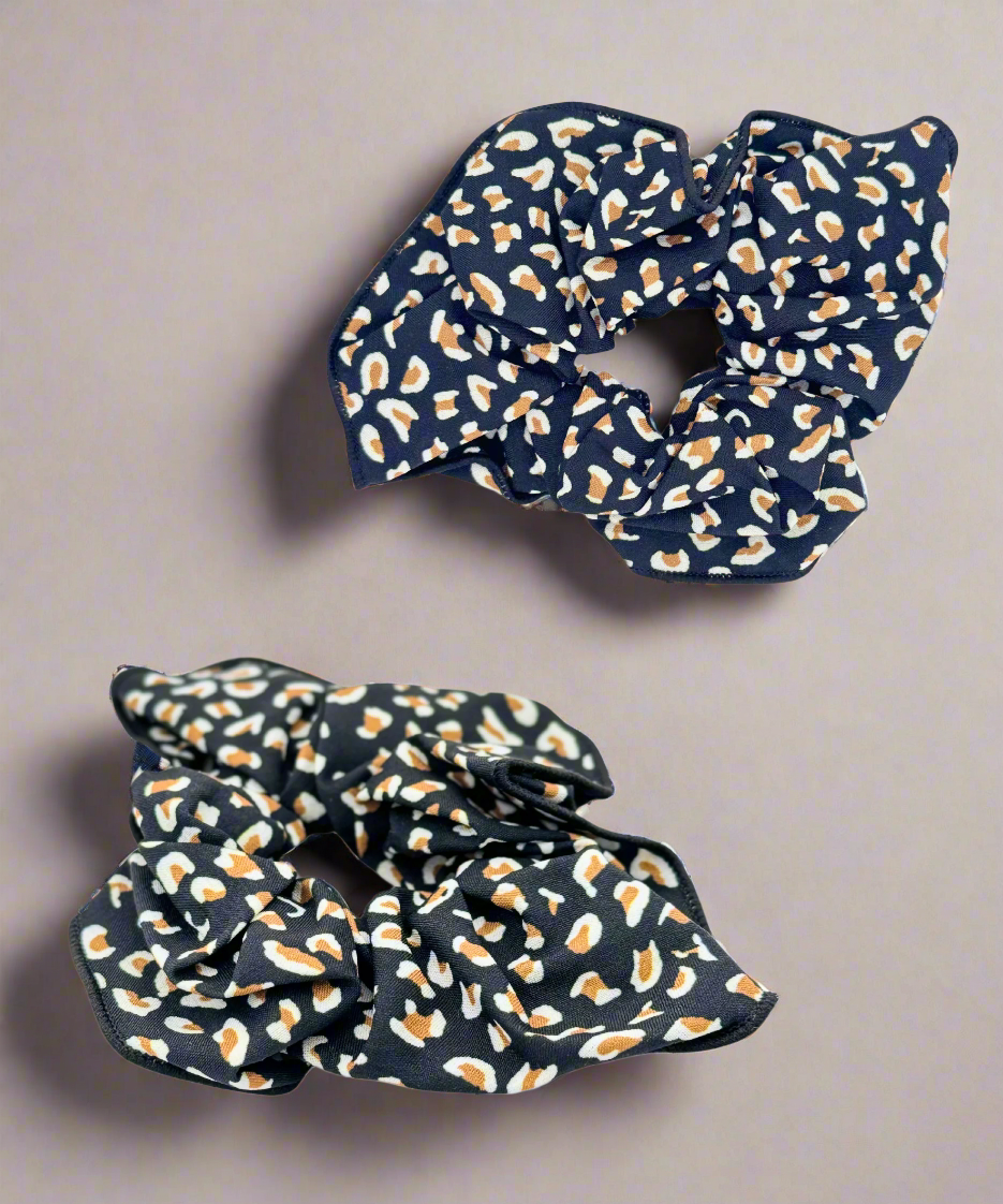 A stylish fabric scrunchie featuring a bold leopard print design, perfect for adding a trendy touch to any hairstyle.