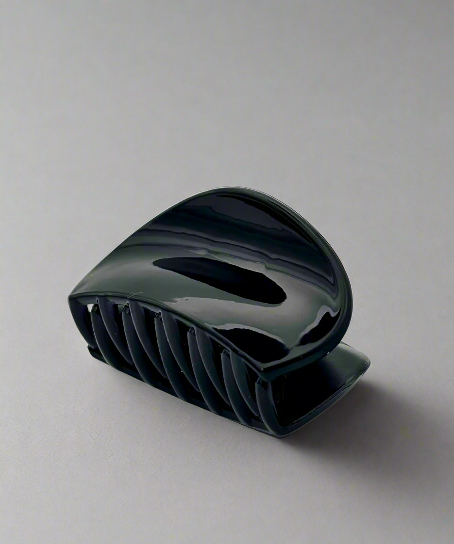 A glossy black hair claw clip with a curved design, offering a secure and comfortable grip for all hair types.