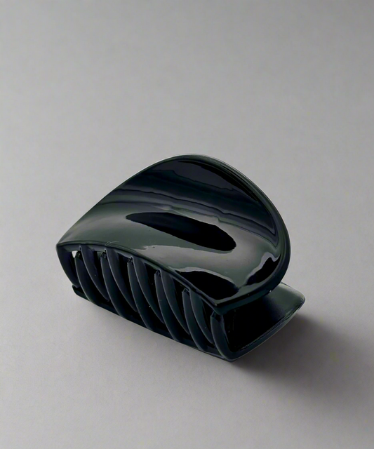 A glossy black hair claw clip with a curved design, offering a secure and comfortable grip for all hair types.