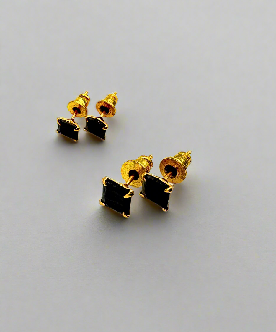 A pair of gold-tone stud earrings with square black stone embellishments, featuring a sleek and modern design.