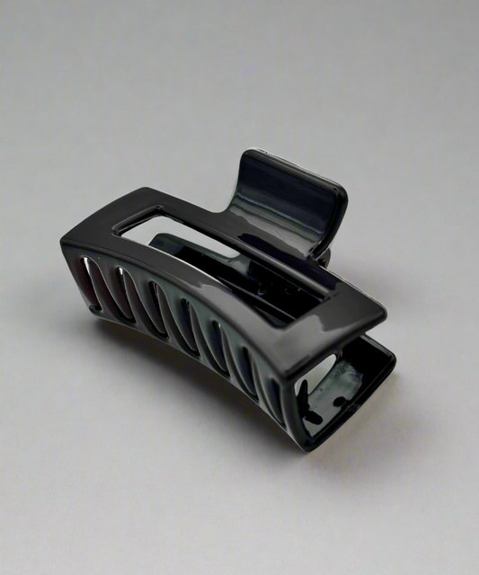 A glossy black hair claw clip with a modern cut-out design, offering a firm grip for all hair types.