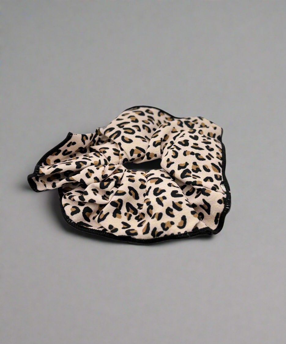 A stylish fabric scrunchie featuring a bold leopard print design, perfect for adding a trendy touch to any hairstyle.