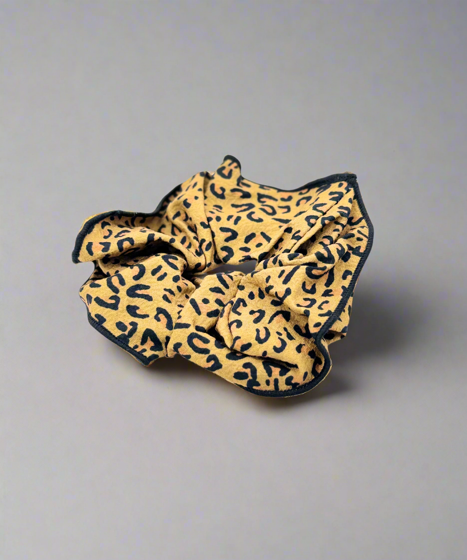 A stylish fabric scrunchie featuring a bold leopard print design, perfect for adding a trendy touch to any hairstyle.