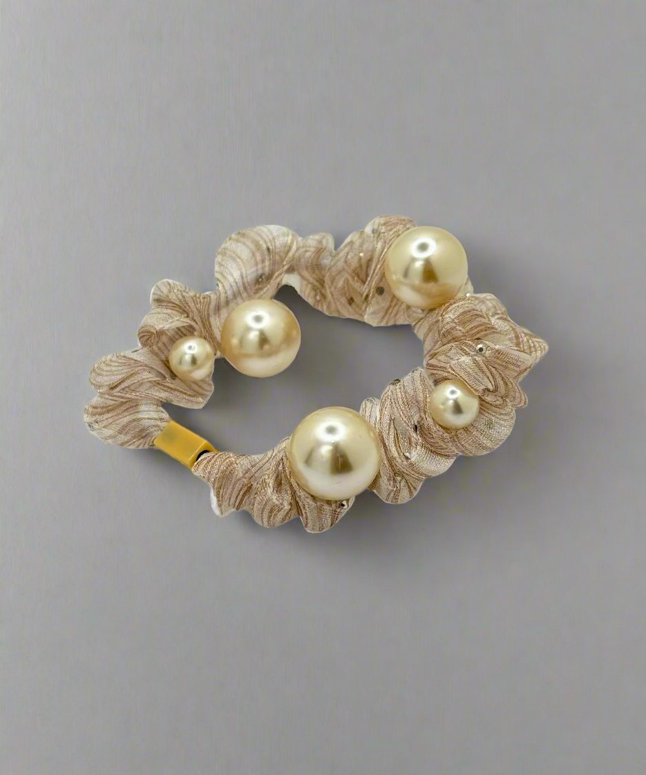 A mesh scrunchie with multiple pearl accents, featuring a delicate and stylish design for an elegant hair look.